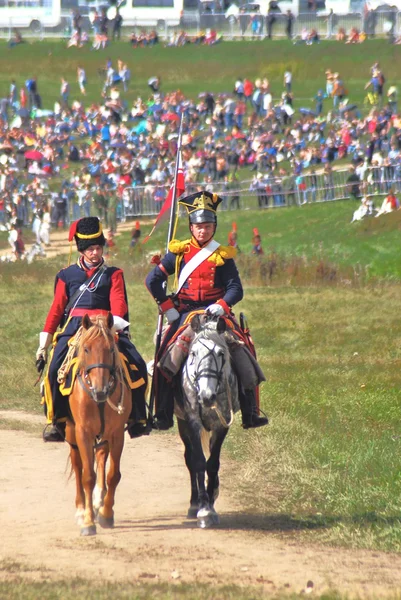 Reenactors dressed as Napoleonic war soldiers ride horses.