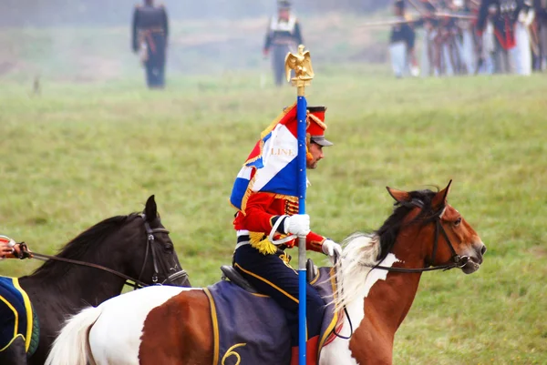 Reenactor dressed as Napoleonic war soldier rides a horse.