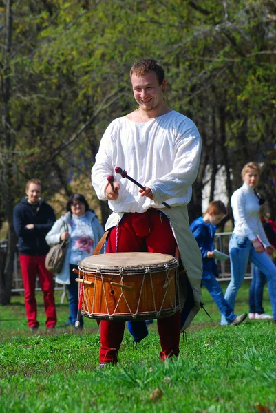 Musician in historical costume play drums in a park