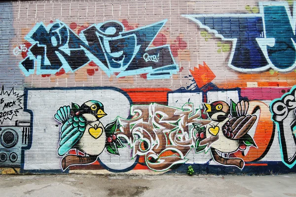 Two birds painted on a brick wall.