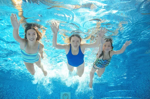 Family swims in pool under water, happy active mother and children have fun underwater, kids sport on family vacation