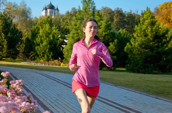 Woman running in autumn park, beautiful girl runner jogging outdoors