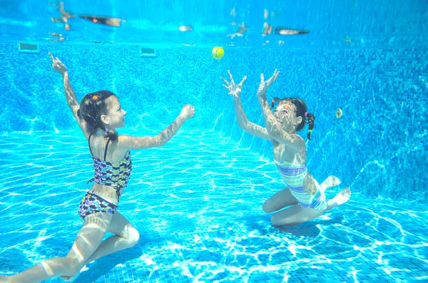 Happy children swim in pool underwater, girls swimming