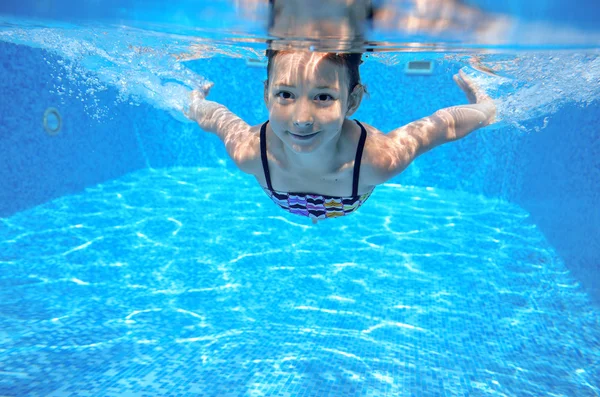 Happy girl swims in pool underwater, active kid swimming