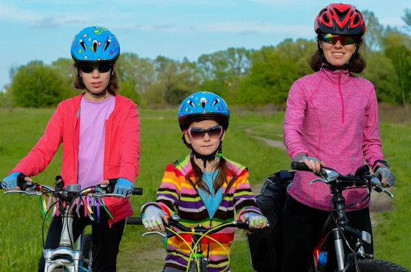 Happy mother and kids on bikes cycling outdoors, active family sport