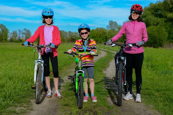 Happy mother and kids on bikes cycling outdoors, active family sport