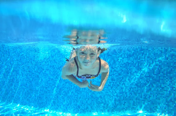 Happy girl swims in pool underwater, active kid swimming, playing and having fun, children water sport