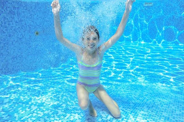 Happy girl swims in pool underwater, active kid swimming, playing and having fun, children water sport