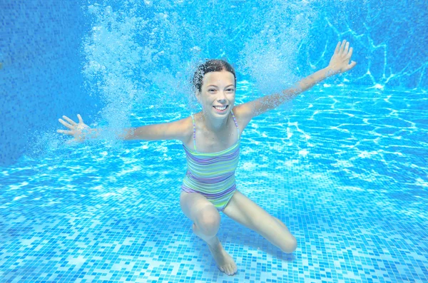 Happy girl swims in pool underwater, active kid swimming, playing and having fun, children water sport