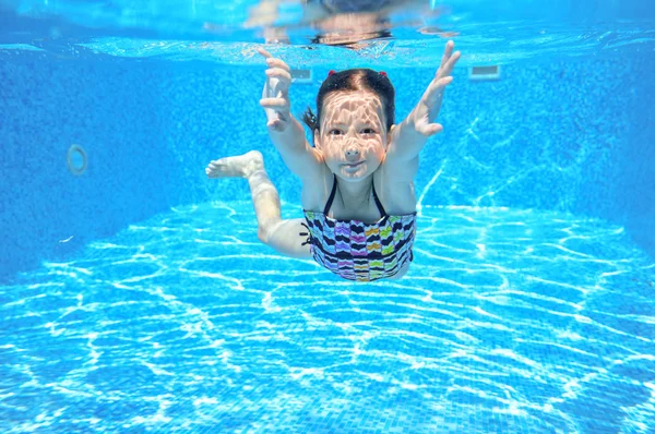 Happy child swims in pool underwater, active kid swimming, playing and having fun, children water sport