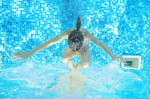 Child swims in pool underwater, happy active girl has fun in water, kid sport on family vacation