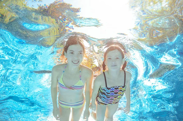 Children swim in pool or sea underwater, happy active girls have fun in water, kids sport on family vacation