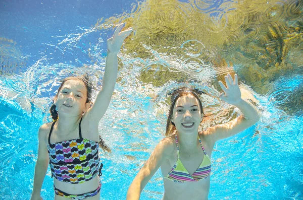 Children swim in pool or sea underwater, happy active girls have fun in water, kids sport on family vacation