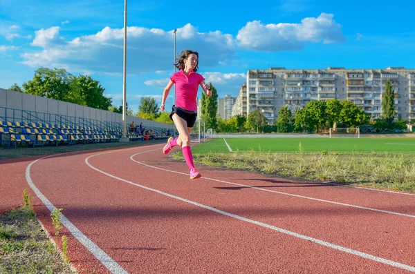 Happy active woman running on track, sprinting and working out on stadium, sport and fitness in city, urban background