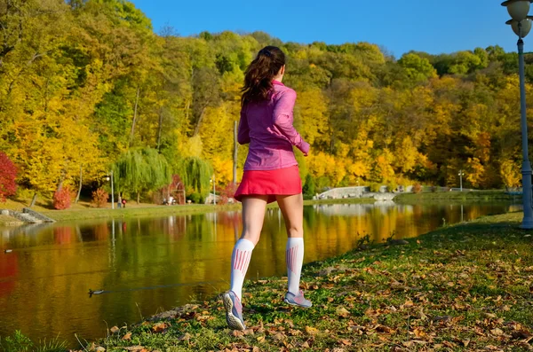 Woman running in autumn park, beautiful girl runner jogging outdoors, training for marathon, exercising and fitness concept