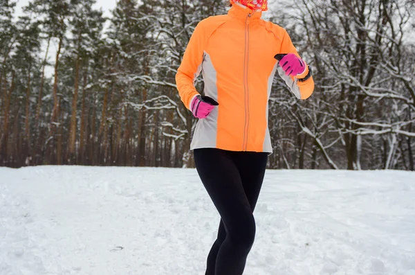 Winter running in forest: happy woman runner jogging in snow, outdoor sport and fitness concept