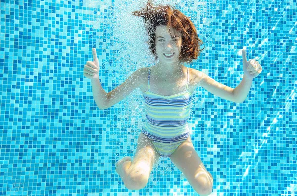 Girl jumps, dives and swims in pool underwater, happy active child has fun under water, kid sport on family vacation