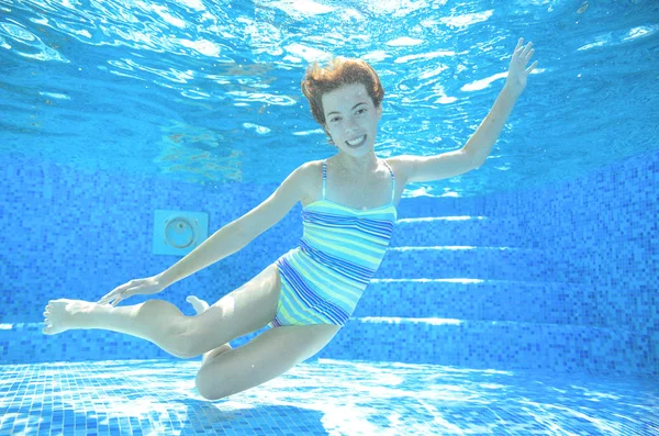 Child swims in pool underwater, happy active girl in goggles has fun under water, kid sport on family vacation