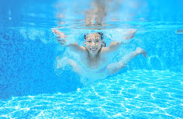 Child swims in pool underwater, happy active girl has fun under water, kid sport on family vacation