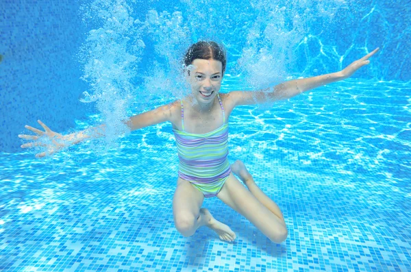 Child swims in pool underwater, happy active girl has fun under water, kid sport on family vacation