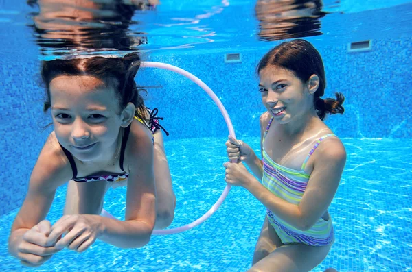 Children swim in pool underwater, happy active girls have fun under water, kids sport on family vacation