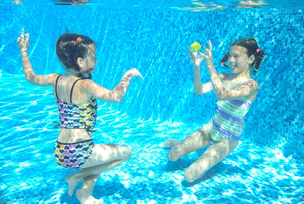 Children swim in pool underwater, happy active girls have fun under water, kids sport on family vacation