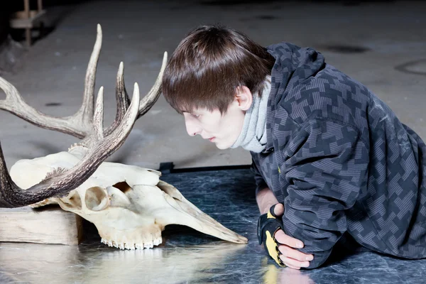 Young man lying down looking at the deer skull