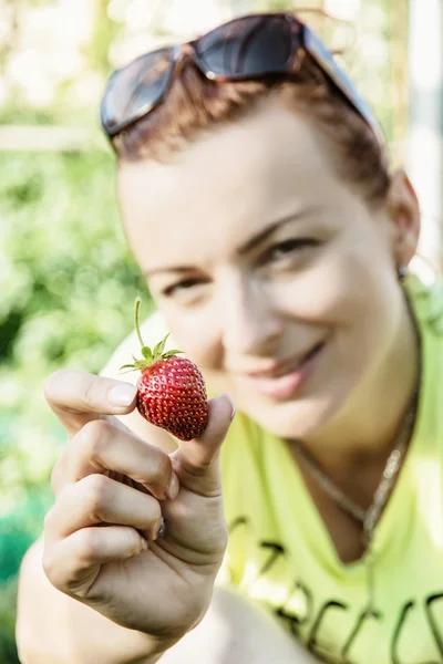 Young woman posing with fresh strawberry, spring garden theme