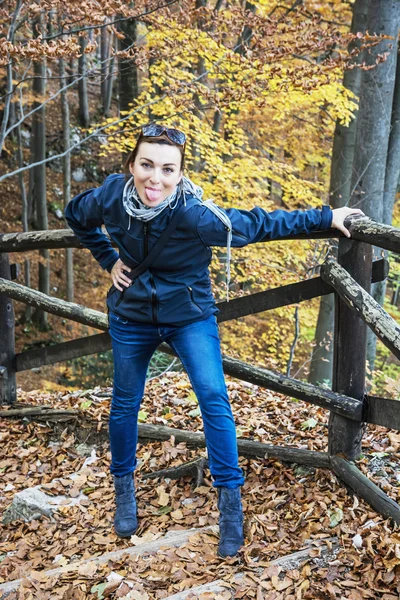 Crazy young woman makes fun in the autumn forest, hiking theme