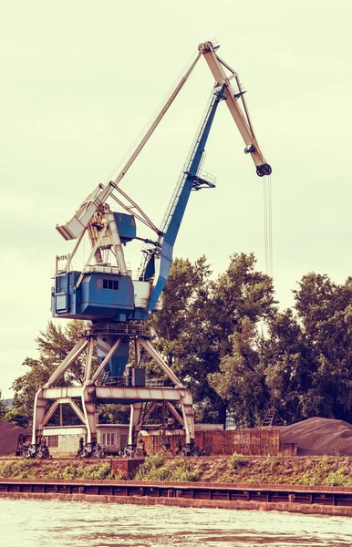 Blue crane in cargo port, retro photo filter