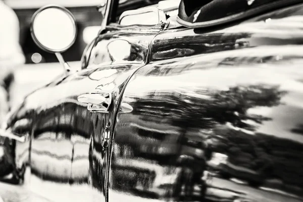 Close up photo of veteran car with rear-view mirror and handle