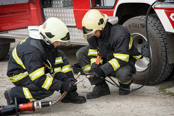 Firemen preparing hydraulic scissors for use by the rescue.