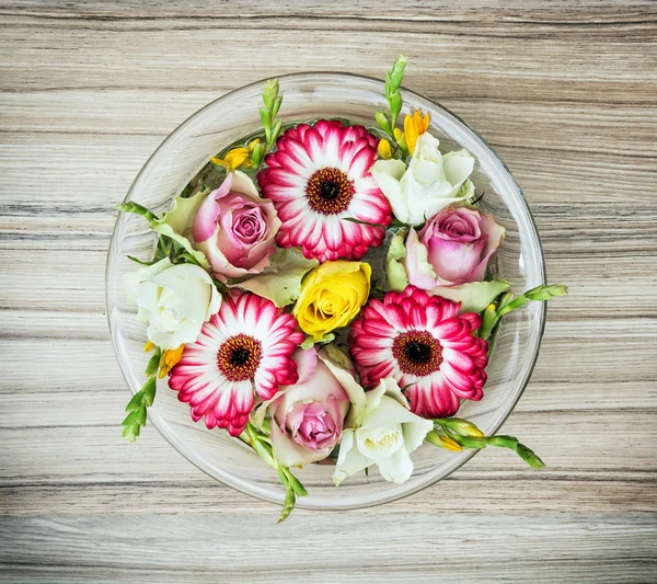 Arangement with roses and gerberas flowers in the glass bowl wit