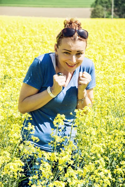 Young woman in the rapeseed field is afraid of insects