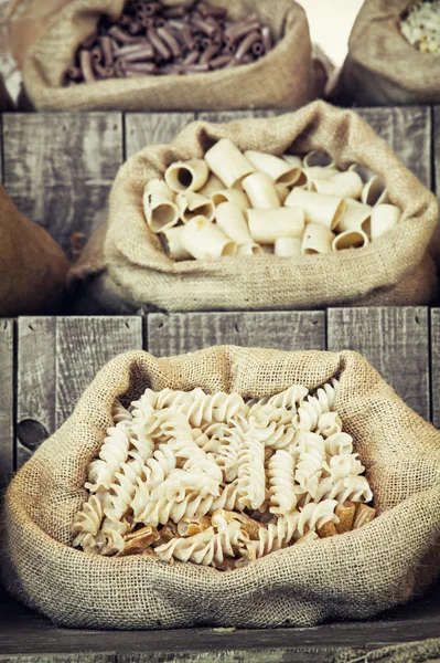Various pasta in canvas bags on the wooden retro board