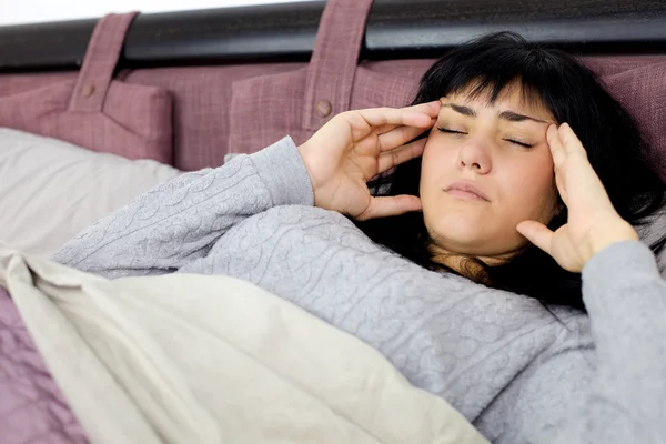 Woman with strong headache and fever lying in bed
