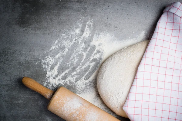 Dough, flour and rolling pin on a stone table