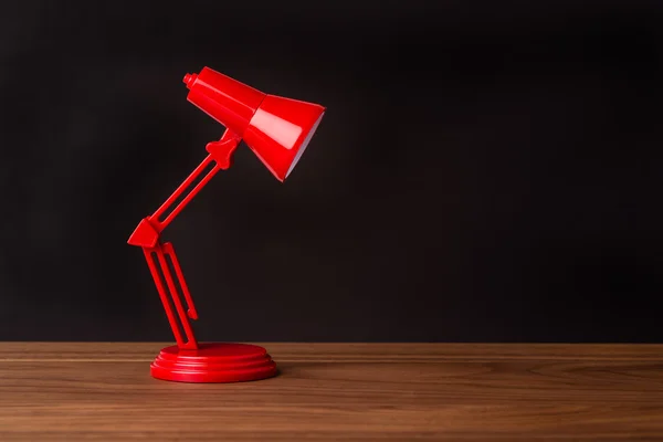 Red metal lamp on a wood desk