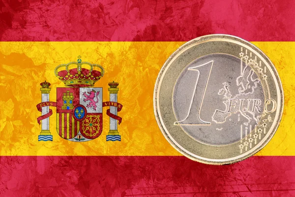 One euro coin on the flag of Spain as background
