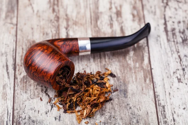 Smoking pipe and tobacco on a wooden table
