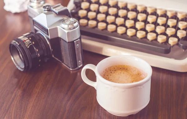 An old typewriter on old wooden table with coffee and old camera