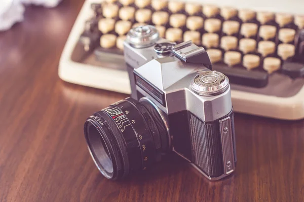 An old typewriter on old wooden table with coffee and old camera