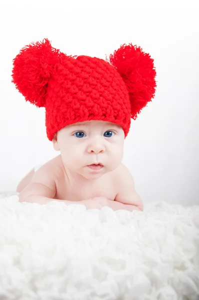 Newborn baby in red hat looking into the camera