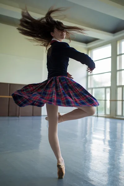 Long-haired ballerina spins in the dance moves on one leg to sta