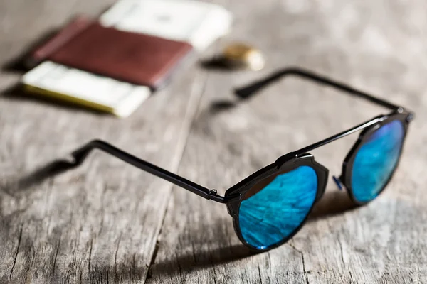 Stylish sunglasses with blue tinted mirror on textured wooden ba