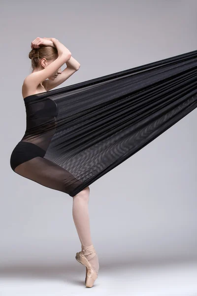 Slim dancer plays with black mesh fabric