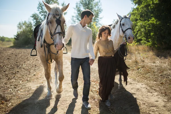 Young couple walking in a picturesque place with horses