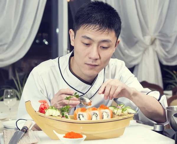 Japanese chef in restaurant making sushi rolls