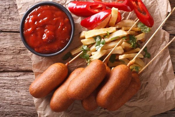 Corn dogs, french fries, pepper and ketchup close-up. horizontal