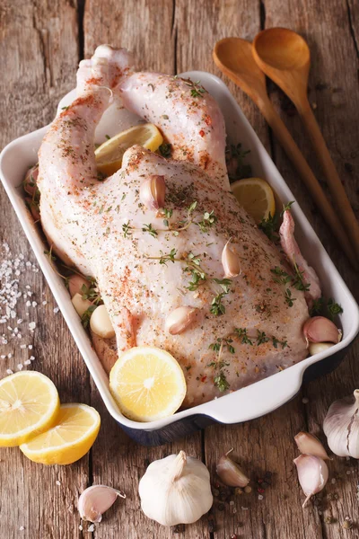 Raw whole chicken marinated with garlic, thyme and lemon close-u